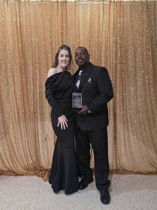 Patrick White at an awards gala holding his 50 Over 50 Award